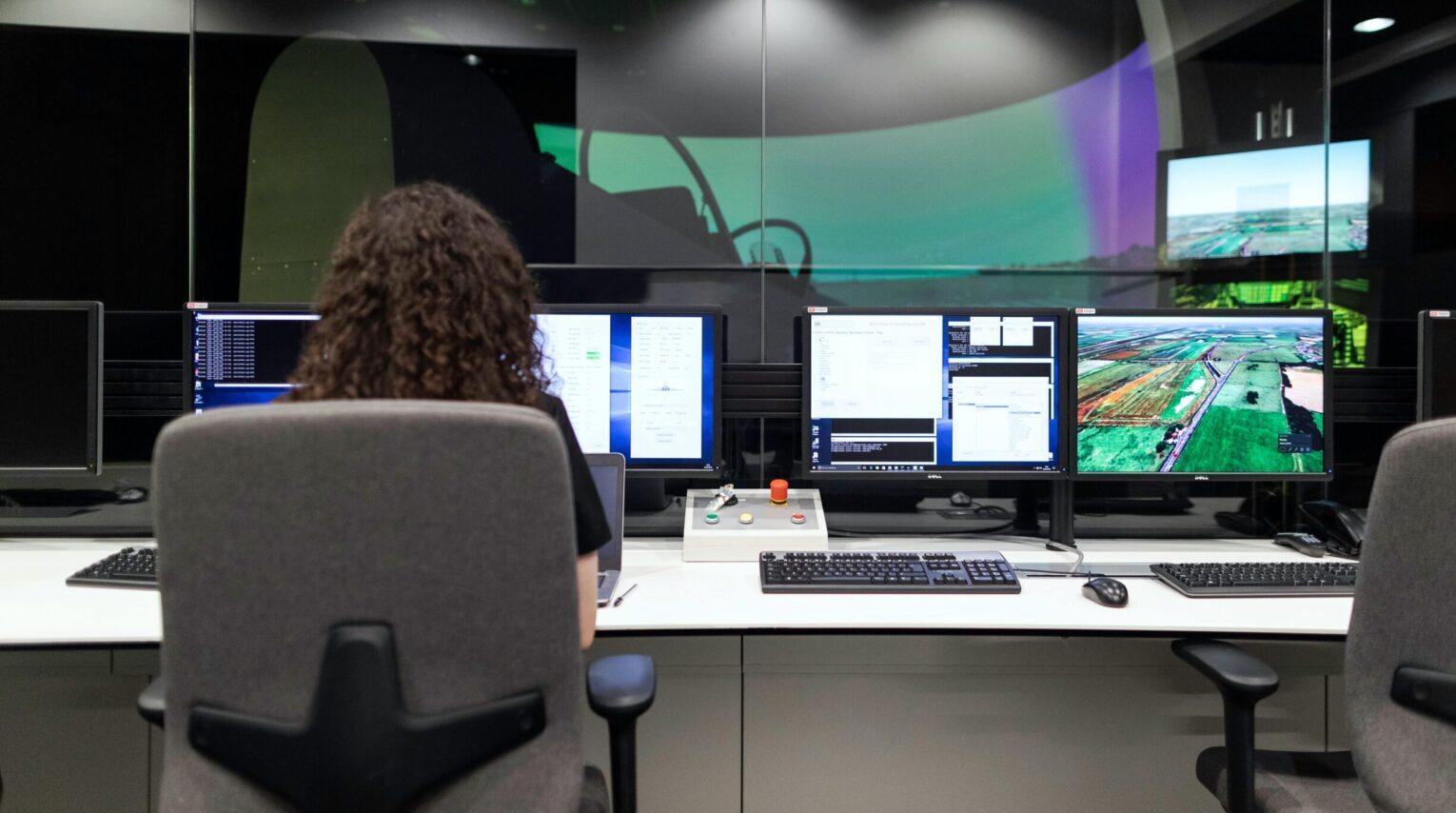 Female engineer managing multiple screens during a technology simulation in a control room.